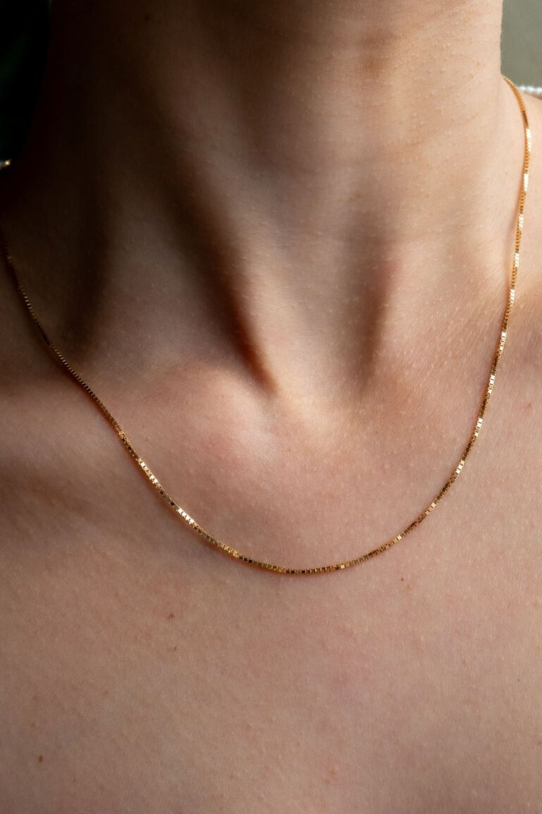 Yellow gold box chain on woman's neck